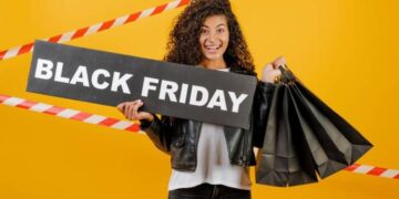 Mulher feliz com placa "Black Friday" e sacolas, representando compras e a importância dos direitos do consumidor.