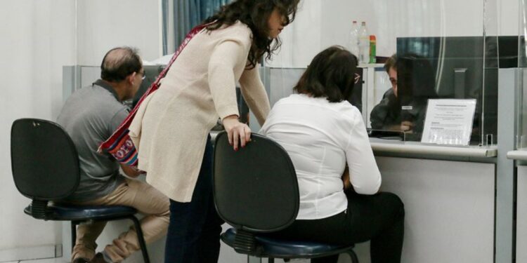 Pessoas sendo atendidas em balcões do INSS, representando a disponibilidade de vagas para atendimento no fim de semana em Minas Gerais.