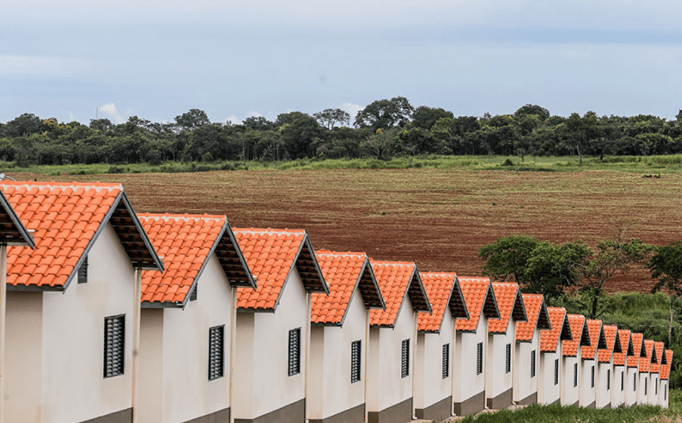 Conjunto de casas populares com telhados laranjas em área residencial.
