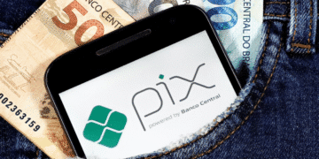 Celular com logo do PIX no bolso de calça jeans ao lado de cédulas do real brasileiro