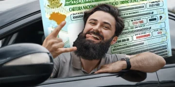Homem sorrindo dentro de um carro, exibindo sua carteira de habilitação, ilustrando a oportunidade do programa CNH Popular 2025