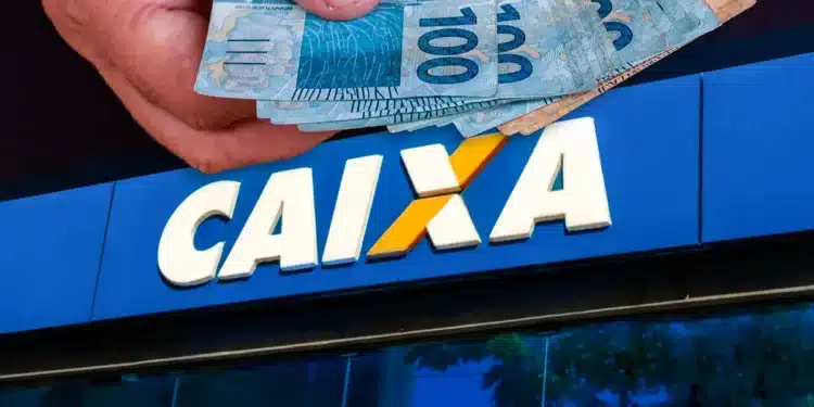Mãos segurando cédulas de 100 reais em frente à agência da Caixa Econômica Federal