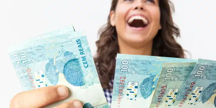 Mulher sorrindo de felicidade, segurando notas de R$ 100 reais, representando o recebimento do 13º salário.