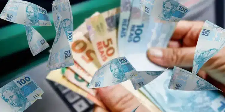 Mãos segurando cédulas brasileiras de 50 e 100 reais com notas voando ao redor