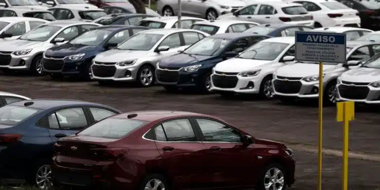 Frota de carros Chevrolet novos estacionados Diversos carros Chevrolet brancos e alguns veículos coloridos estacionados em fila em área de estacionamento