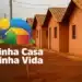Casas populares com telhado de cerâmica alinhadas em rua de terra vermelha no programa Minha Casa Minha Vida