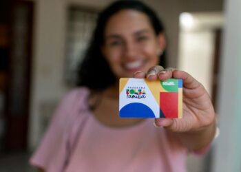 Mulher segurando o cartão do Bolsa Família, simbolizando a liderança feminina nas famílias beneficiadas.