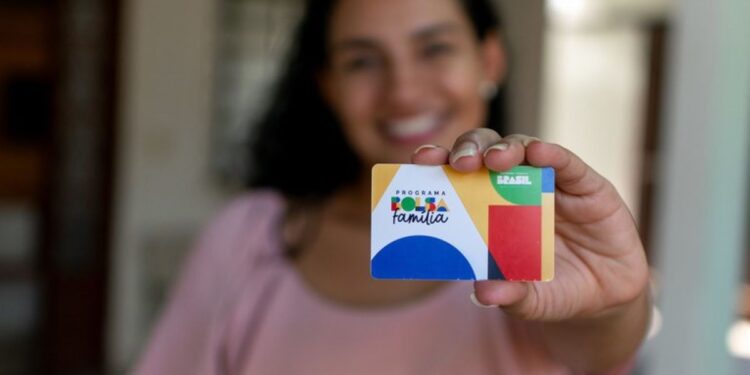Mulher segurando o cartão do Bolsa Família, simbolizando a liderança feminina nas famílias beneficiadas.