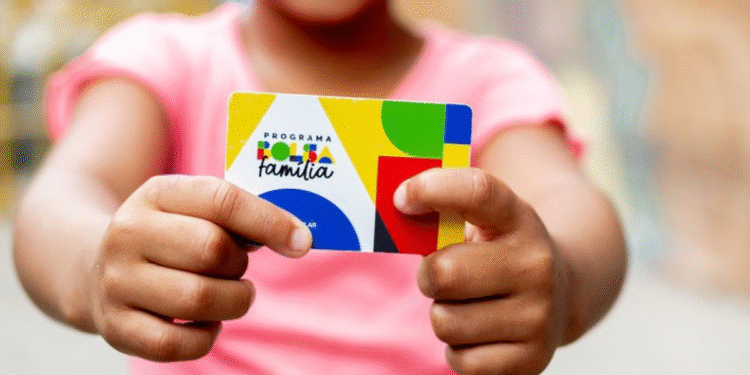 Criança segurando um cartão do Programa Bolsa Família com as duas mãos.