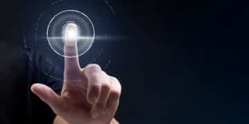 Dedo de uma pessoa tocando um leitor de impressão digital holográfico, com círculos de tecnologia, simbolizando segurança, identificação e o uso de biometria.