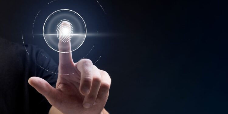 Dedo de uma pessoa tocando um leitor de impressão digital holográfico, com círculos de tecnologia, simbolizando segurança, identificação e o uso de biometria.