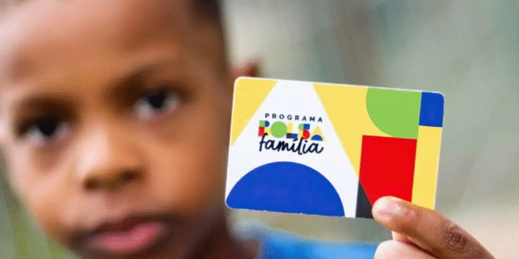 Criança segurando cartão do Programa Bolsa Família em close-up, com foco no cartão colorido.