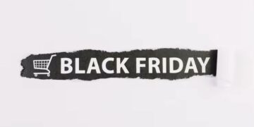 Faixa preta rasgada em papel branco com a inscrição 'Black Friday' e um ícone de carrinho de compras, simbolizando a abertura de ofertas.