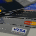 Vários cartões de crédito das bandeiras Visa e Mastercard empilhados.