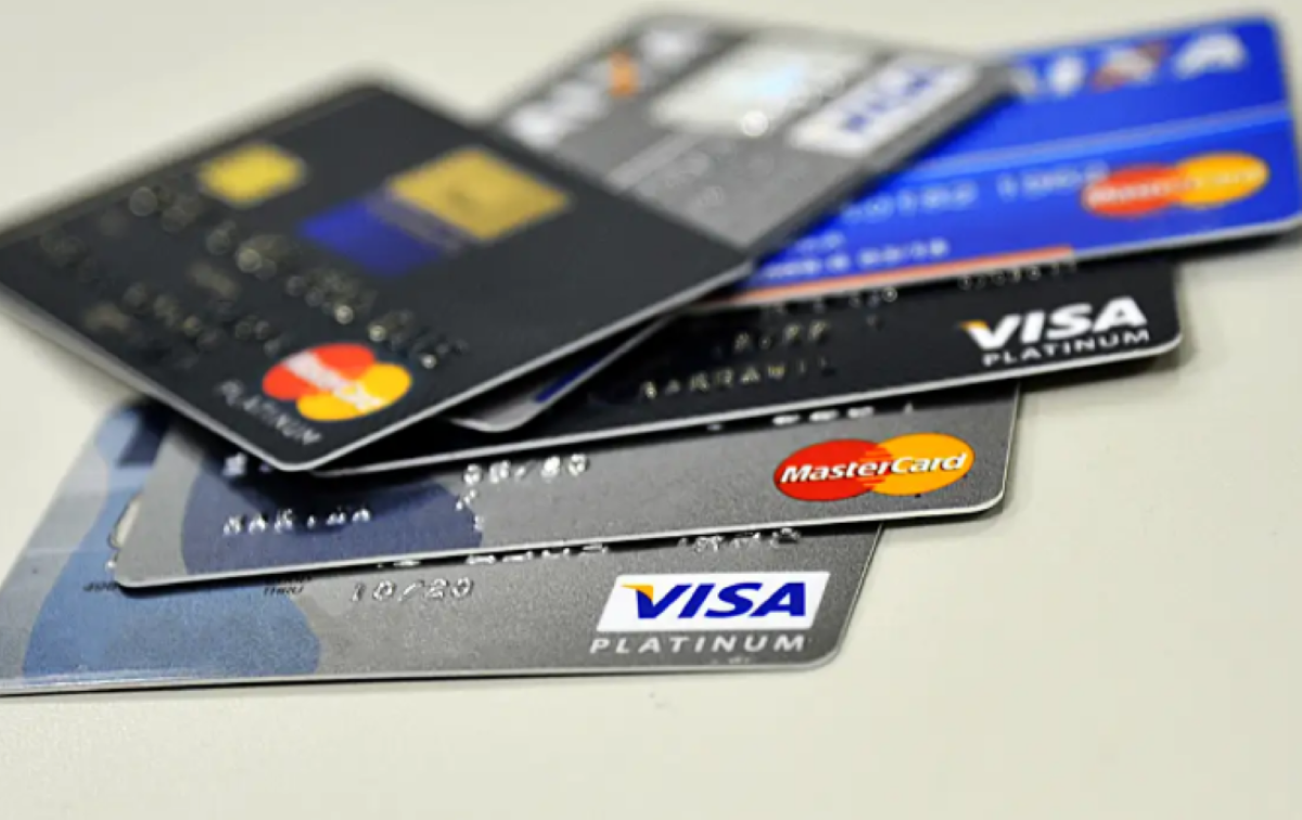 Vários cartões de crédito das bandeiras Visa e Mastercard empilhados sobre uma superfície.