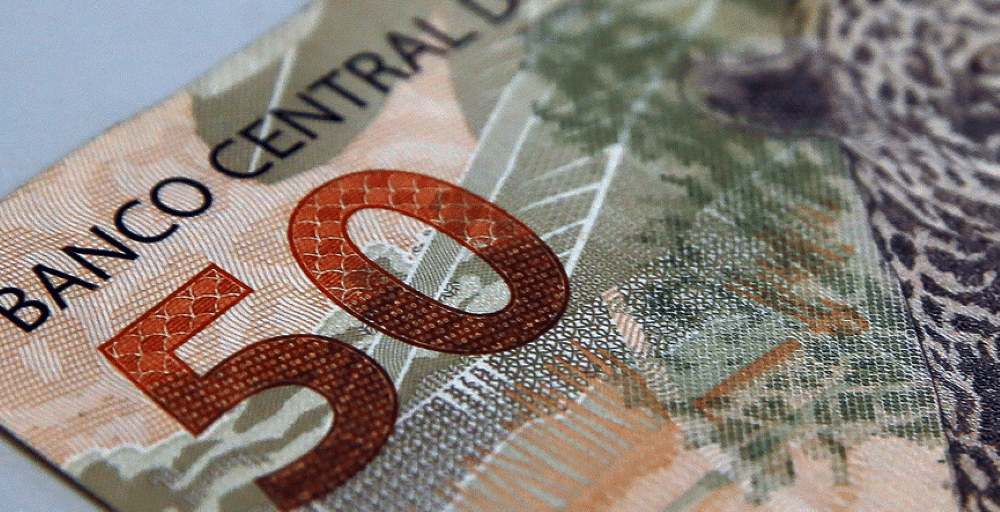 Nota de 50 Reais Representando Pagamento de Benefícios Close-up de uma nota de 50 reais do Banco Central do Brasil, destacando o valor e elementos de segurança.