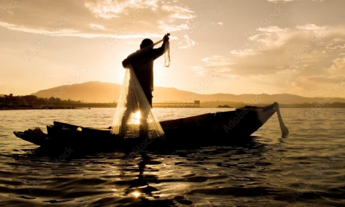Pagamento retroativo do Seguro-Defeso é liberado pelo INSS Pescador em um barco lançando rede ao amanhecer.