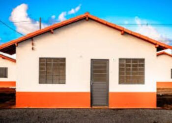 Fachada de uma casa popular com telhado laranja e detalhes na parede, sob um céu azul, representando o sonho da casa reformada com o crédito Reforma Casa Brasil da Caixa.