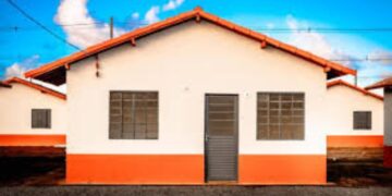 Fachada de uma casa popular com telhado laranja e detalhes na parede, sob um céu azul, representando o sonho da casa reformada com o crédito Reforma Casa Brasil da Caixa.