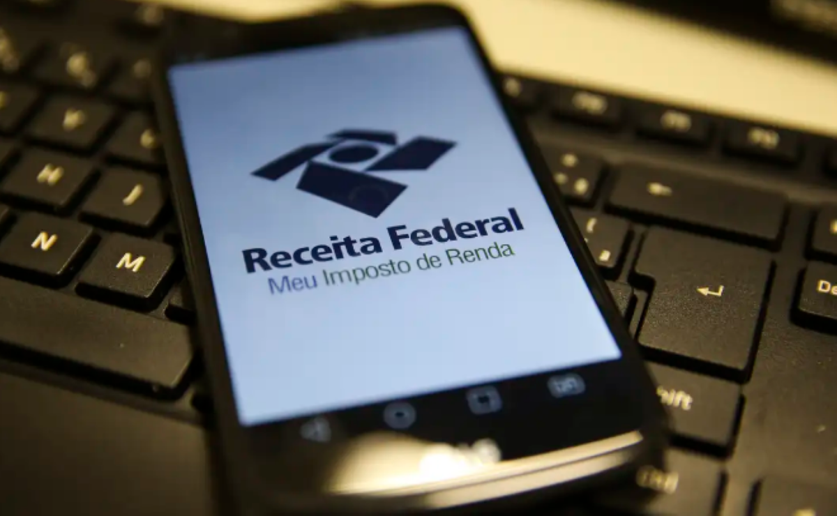 Nova isenção do Imposto de Renda aumenta o salário dos trabalhadores em 2026 Celular com o aplicativo da Receita Federal aberto sobre um teclado de computador.