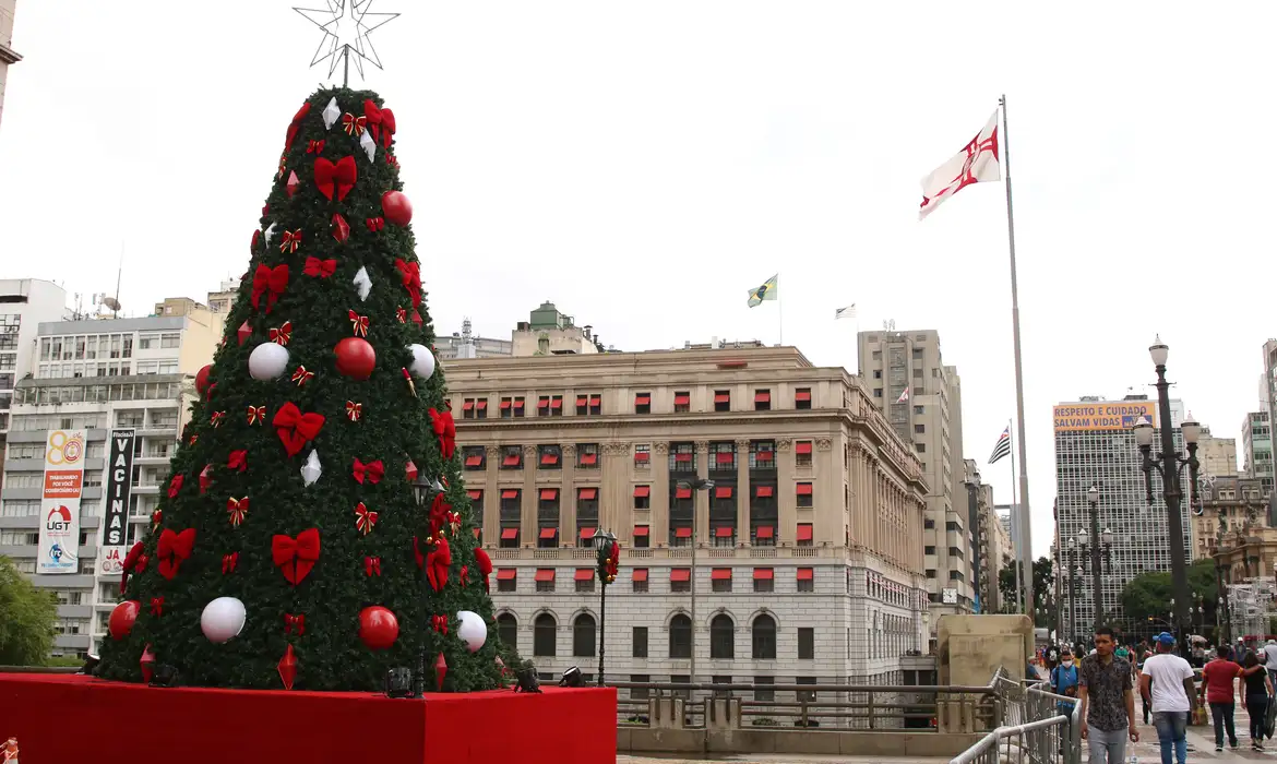 Árvore de Natal decorada em área urbana de São Paulo Árvore de Natal verde decorada com laços vermelhos, bolas brancas e vermelhas em praça pública de São Paulo