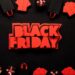 A frase "BLACK FRIDAY" em vermelho sobre fundo preto, cercada por pequenas caixas de presente e sacolas, simbolizando compras e ofertas.