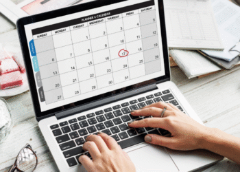Laptop exibindo calendário digital com o dia 17 circulado em vermelho, ao lado de agenda física, destacando planejamento para o feriado de 15 de novembro.