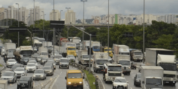 Tráfego intenso com diversos veículos em rodovia urbana brasileira.