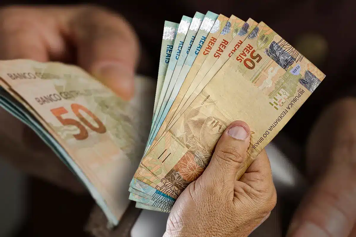 Dinheiro do 13º salário Notas de 50 reais em mãos, representando o 13º salário não pago.