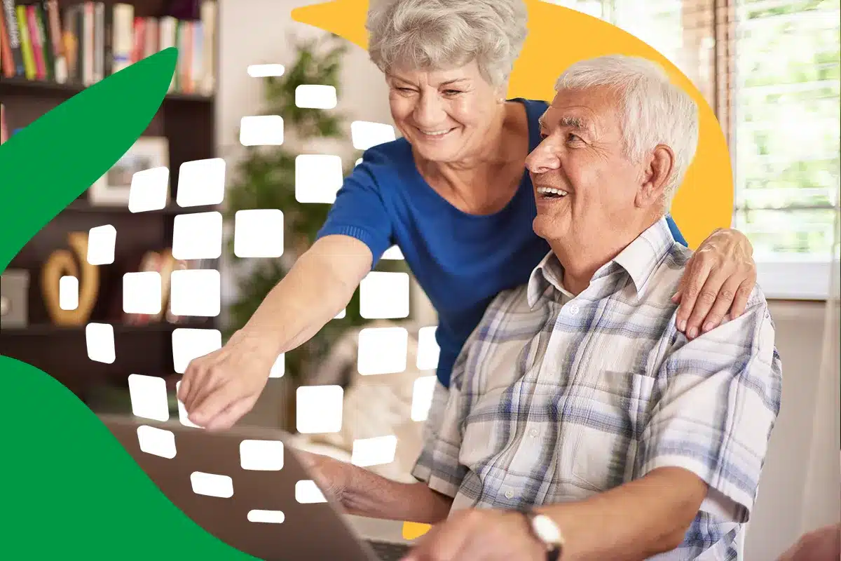 como consultar extrato pagamento meu inss Um casal de idosos sorridentes, uma mulher de blusa azul e um homem de camisa xadrez, olhando para a tela de um notebook enquanto o logotipo da Previdência Social aparece sobreposto à imagem.