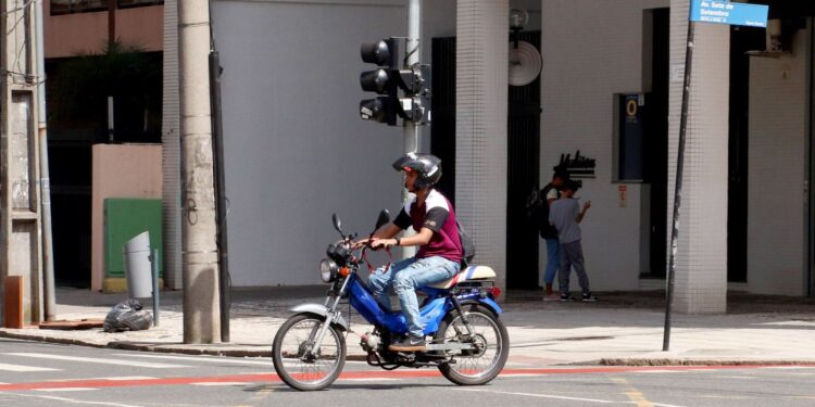 Motociclista com ciclomotor, símbolo das novas regras de registro, emplacamento e requisitos para condutores a partir de 2026.