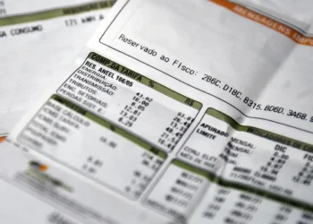 Close-up de faturas de energia elétrica sobrepostas, com destaque para a seção "Composição da Tarifa", ilustrando a redução de custos para famílias de baixa renda.