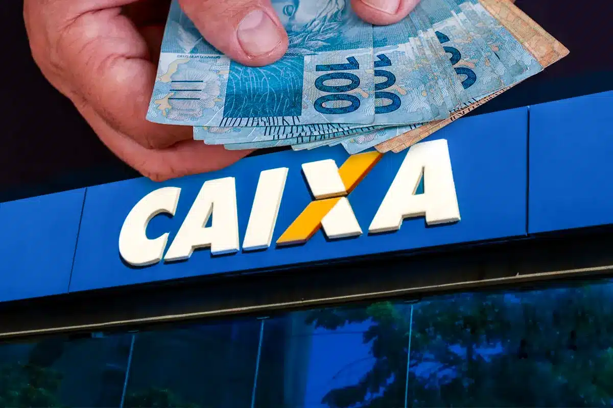 Mão segurando notas de real sobre fachada da Caixa Econômica Federal