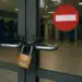 Porta de vidro com corrente e cadeado em agência bancária vazia