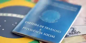 Carteira de Trabalho e Previdência Social azul posicionada sobre bandeira do Brasil com notas de 2 reais visíveis.