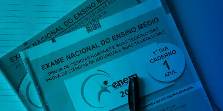 Close de dois cadernos de prova oficiais do Enem (um rosa e um azul) empilhados, sob uma iluminação azul ciano. Uma caneta preta está posicionada na parte inferior do caderno azul, que exibe "1º DIA - CADERNO 1 AZUL".