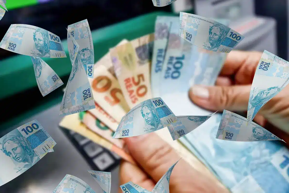 Mão segurando notas de real em meio a cédulas voando representando o pagamento do abono salarial PIS/Pasep