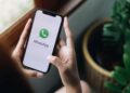 Pessoa segurando celular com aplicativo WhatsApp aberto, recebendo mensagem