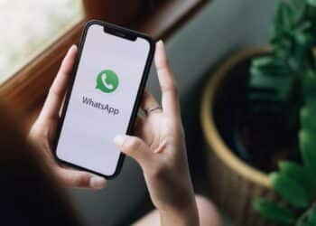 Pessoa segurando celular com aplicativo WhatsApp aberto, recebendo mensagem