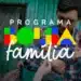 Homem segurando bebê em frente a parede verde, com mãos entregando criança e logotipo colorido do Bolsa Família sobreposto