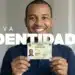 Homem sorridente segura Carteira de Identidade Nacional (CIN) verde com brasão do Brasil e dados pessoais.