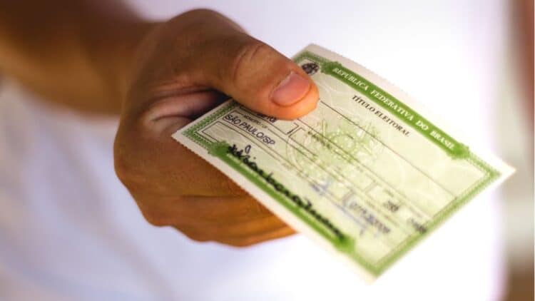 Mão segurando título eleitoral da República Federativa do Brasil, emitido em São Paulo/SP.