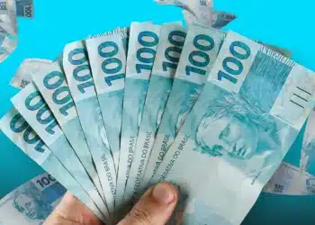 Notas de 100 reais espalhadas e em leque representando pagamentos e benefícios