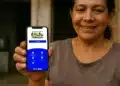 Mulher mostrando celular com aplicativo do Bolsa Família aberto