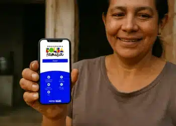 Mulher mostrando celular com aplicativo do Bolsa Família aberto