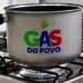 Panela de alumínio sobre fogão a gás com chama azul e logo colorido do programa Gás do Povo.