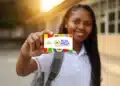 Jovem estudante negra com uniforme branco e mochila mostrando cartão do Pé-de-Meia