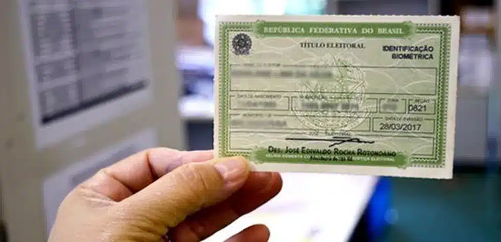 Mão segurando título eleitoral verde da República Federativa do Brasil com data de emissão 28/03/2017