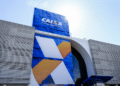 Fachada azul de agência Caixa Econômica Federal com logo X estilizado em branco e laranja contra céu azul.