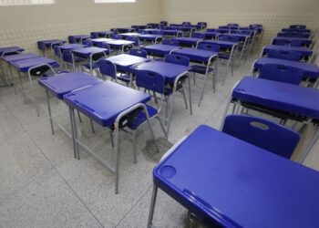 Sala de aula vazia com carteiras azuis enfileiradas